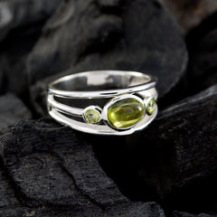 Putri trendy green gemstone ring with oval and round stones set in silver band on dark textured background