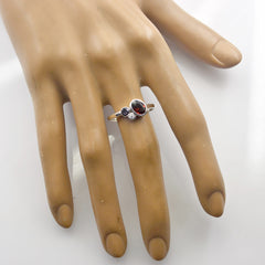 Yan trendy red gemstone ring with silver band and smaller accent stones on display hand