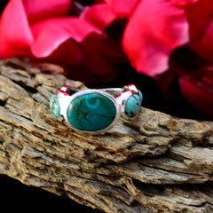 Turquoise gemstone ring by Fernanda with three oval stones set in silver band on textured wood