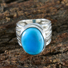 Ellie turquoise solitaire ring with a large oval blue stone set in a silver band on a textured wood background