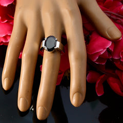 Natcha vintage red solitaire ring with a dark red gemstone on a display hand with red flower background