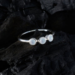 Ling white gemstone ring for women with three round stones set on a silver band on black textured background