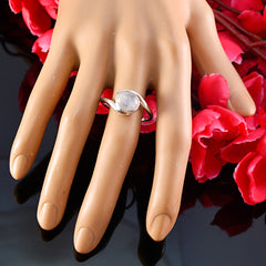 Bruna white solitaire gemstone ring in silver on mannequin hand display with pink rose backdrop