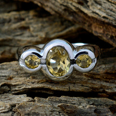 Priya silver yellow gemstone trilogy ring with central oval and two round accent stones on wood background