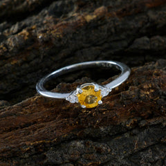 Xiu yellow gemstone trilogy ring with silver band and three yellow stones on rustic wooden surface