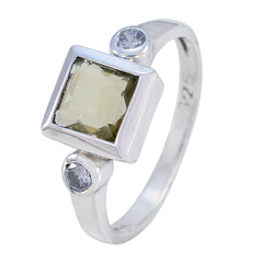 Nisa silver ring with green center stone and two clear side stones yellow trilogy ring