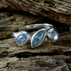 Laura artisan blue gemstone ring with three blue stones set in silver band on rustic wood