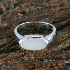 Ayesha white solitaire ring with oval moonstone bezel set in sterling silver band on bark