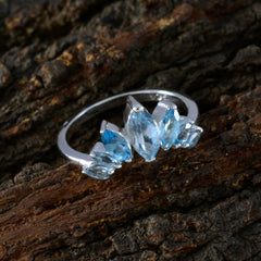 Eleanor blue gemstone crown ring with multiple blue stones set in silver band on textured wood