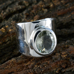 Angel light green solitaire ring with a wide silver band on a natural wood background