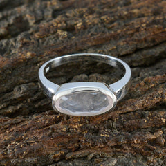Soo-jin pink solitaire ring for women with oval gemstone set in silver band on textured wood
