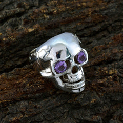 Isadora silver skull ring with purple gemstone skull ring design on textured bark background