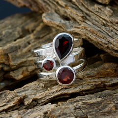 Paula statement red gemstone ring with three red stones set in silver bands on rustic wood