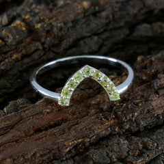Naomi green gemstone crown ring with delicate silver band on textured bark background
