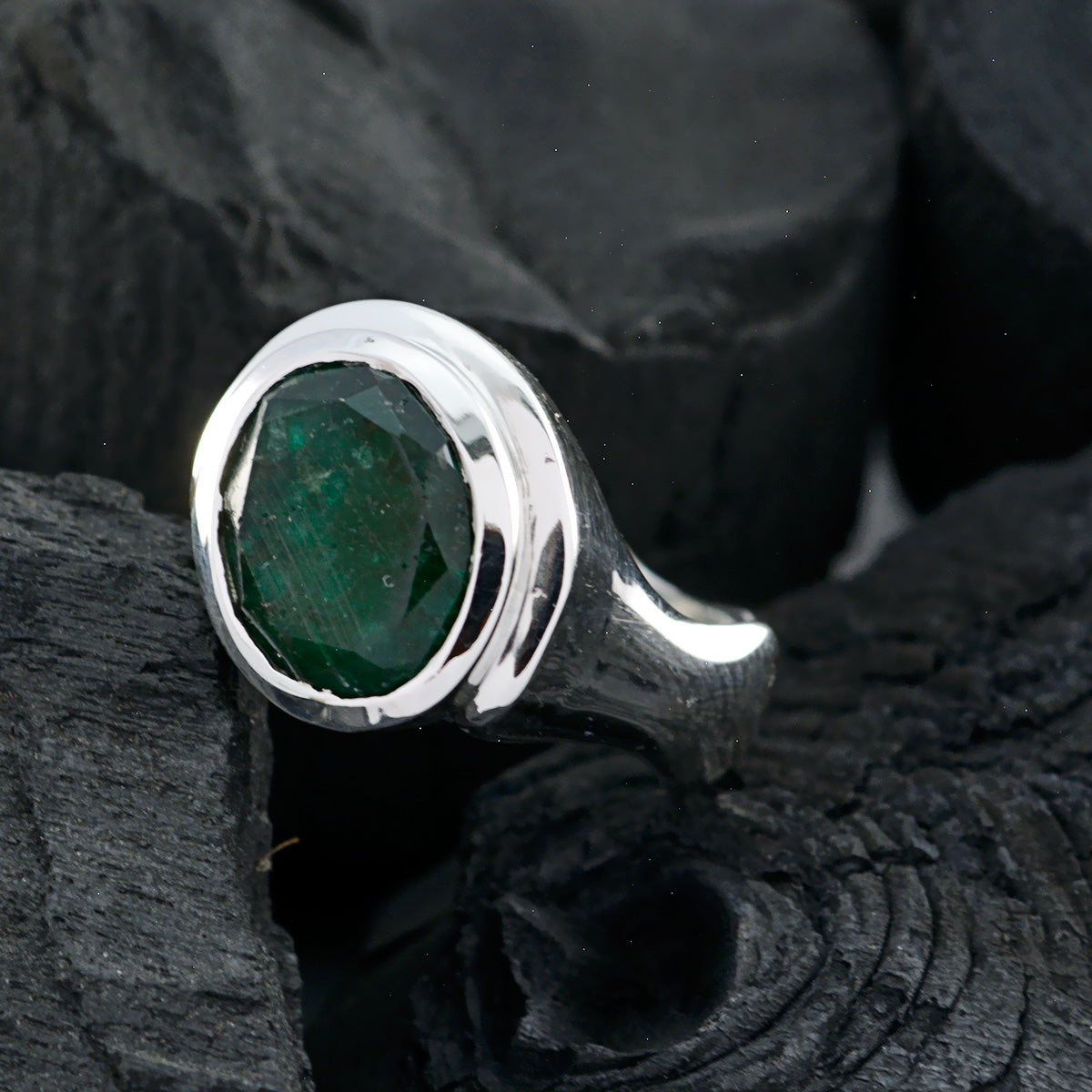 Savannah green solitaire ring with oval faceted emerald in polished silver bezel and tapered band
