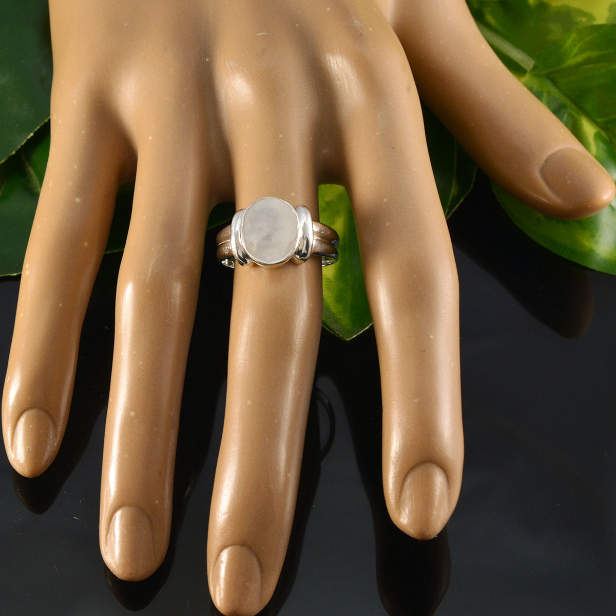 Katarina artisan white solitaire ring featured on a display hand against a green backdrop