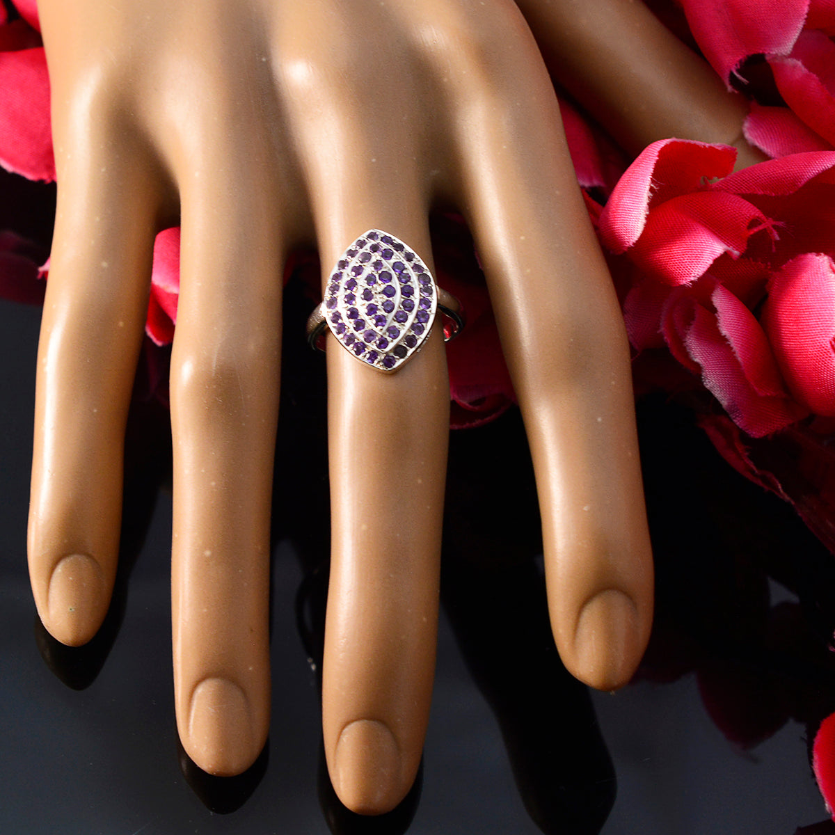Priya abstract purple gemstone ring in marquise cluster setting on silver band displayed on hand with pink petals