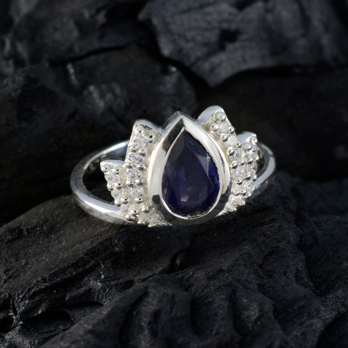 Dewi blue gemstone halo ring with pear-shaped blue stone and silver setting on black background