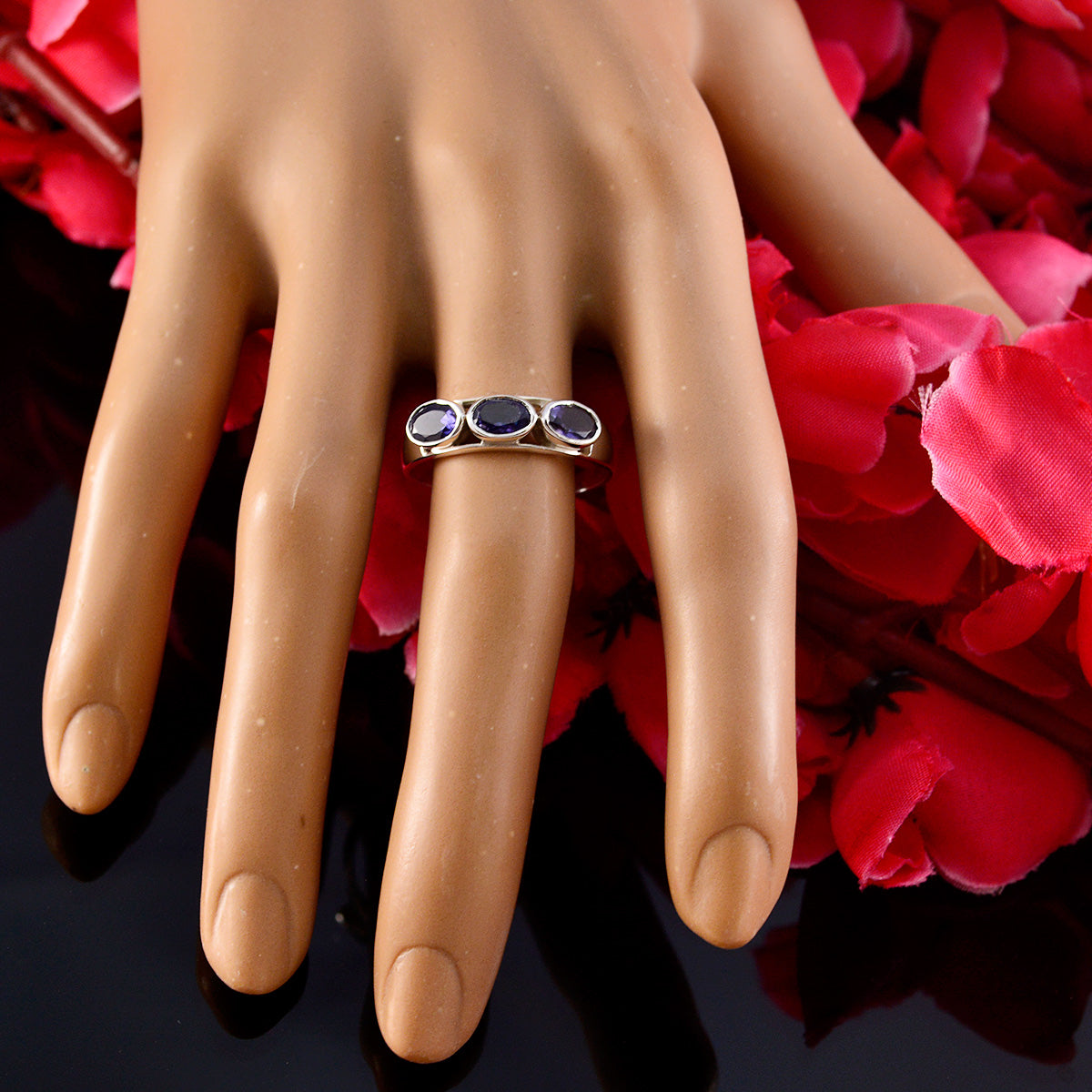 Lily blue trilogy gemstone ring with three blue stones on gold band displayed on mannequin hand