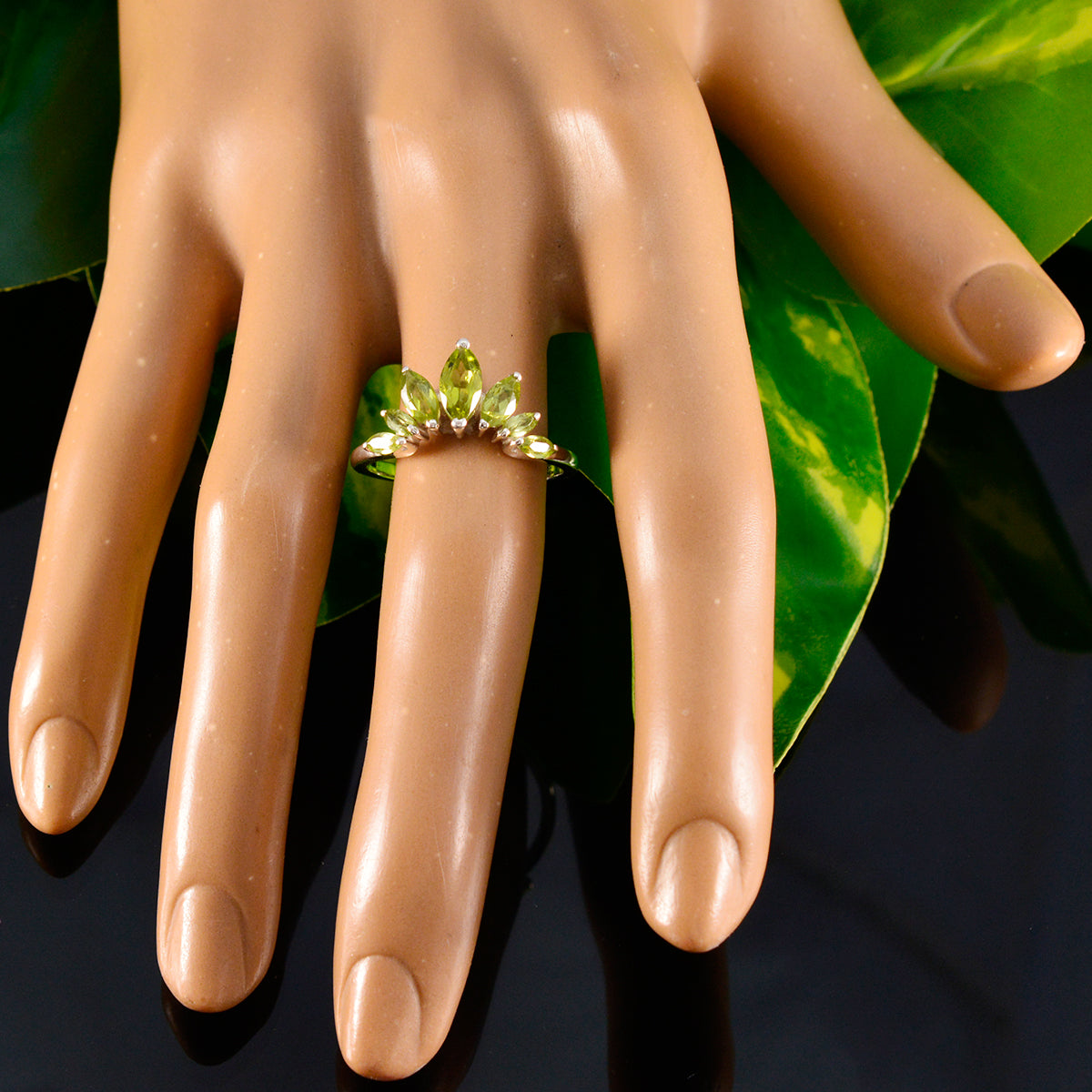 Kristine green gemstone crown ring on mannequin hand with green leaves background