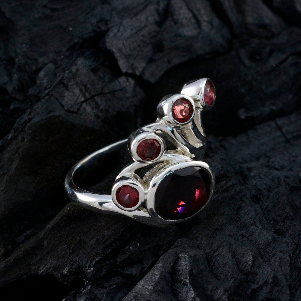 Nayara modern red gemstone ring with multiple red stones set in silver band on dark textured background