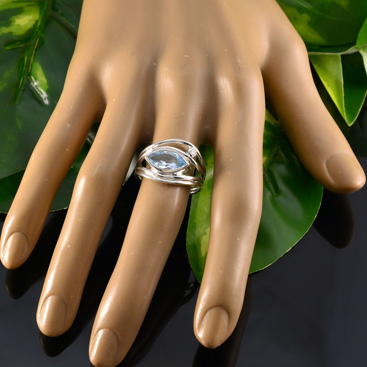 Putri blue abstract toi et moi ring with silver band on display hand over green leaves