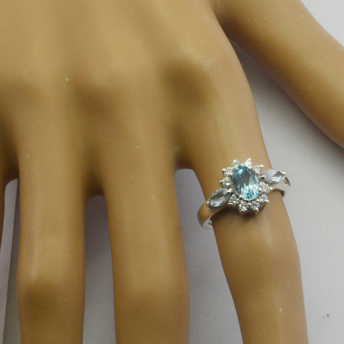 Lili blue gemstone trilogy ring with three blue gems and silver band on a display hand