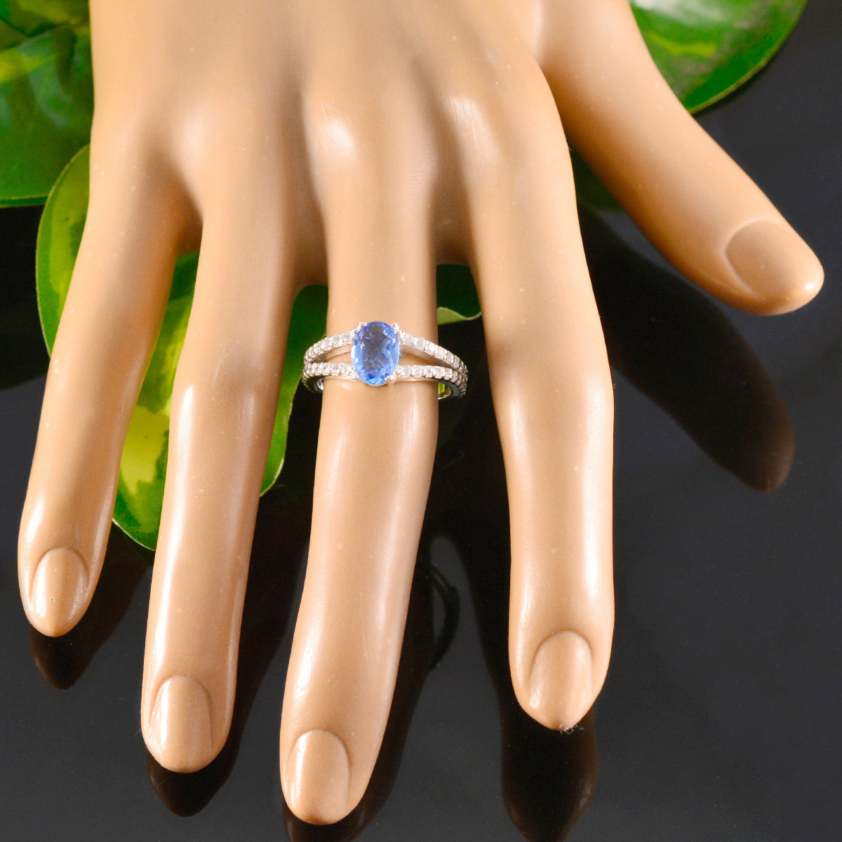 Teresa blue halo gemstone ring with oval blue stone and sparkling band on model hand