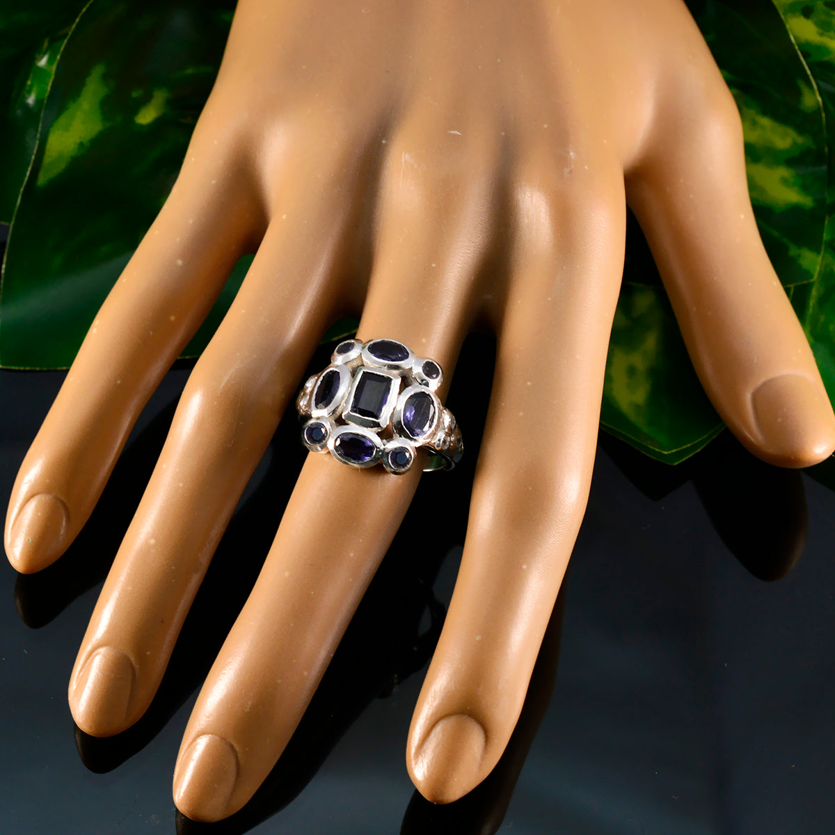 Emma blue navratna ring sterling silver with central square stone and surrounding oval blue gemstones on a model hand