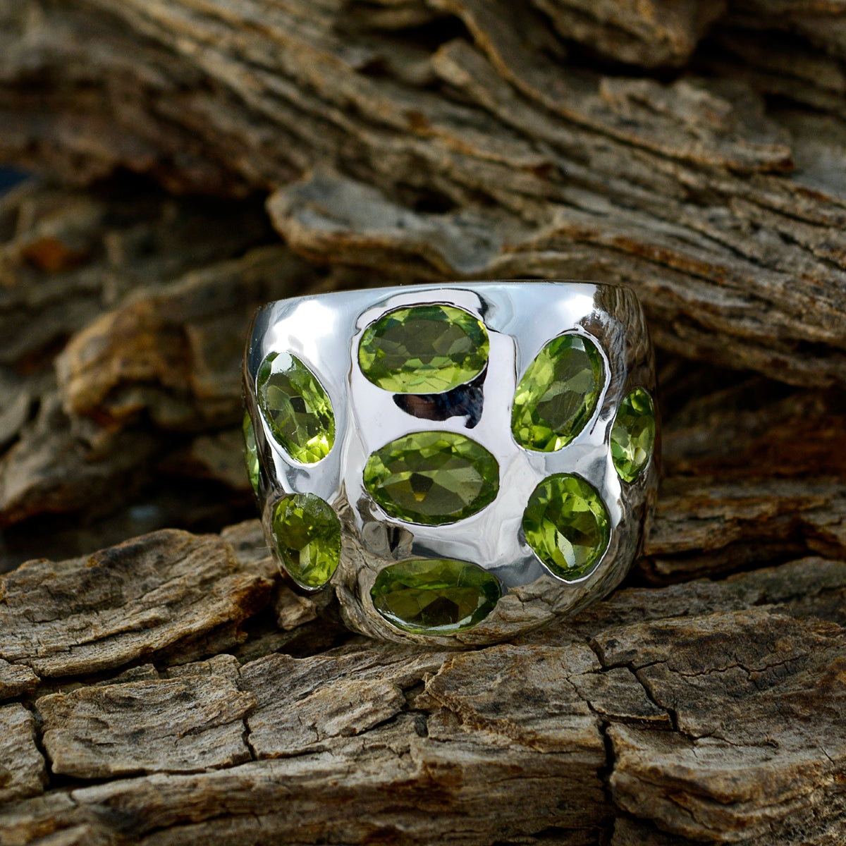Camila green navratna ring with multiple oval green gemstones set in silver band on wood