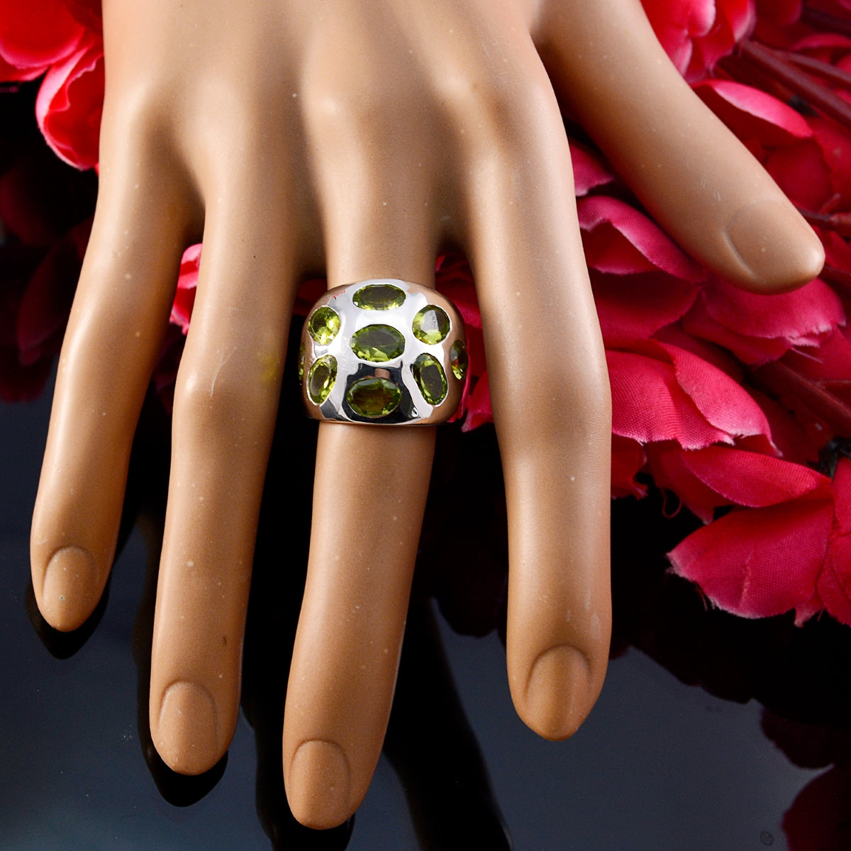 Camila green navratna ring with multiple green gemstones set in silver on a display hand