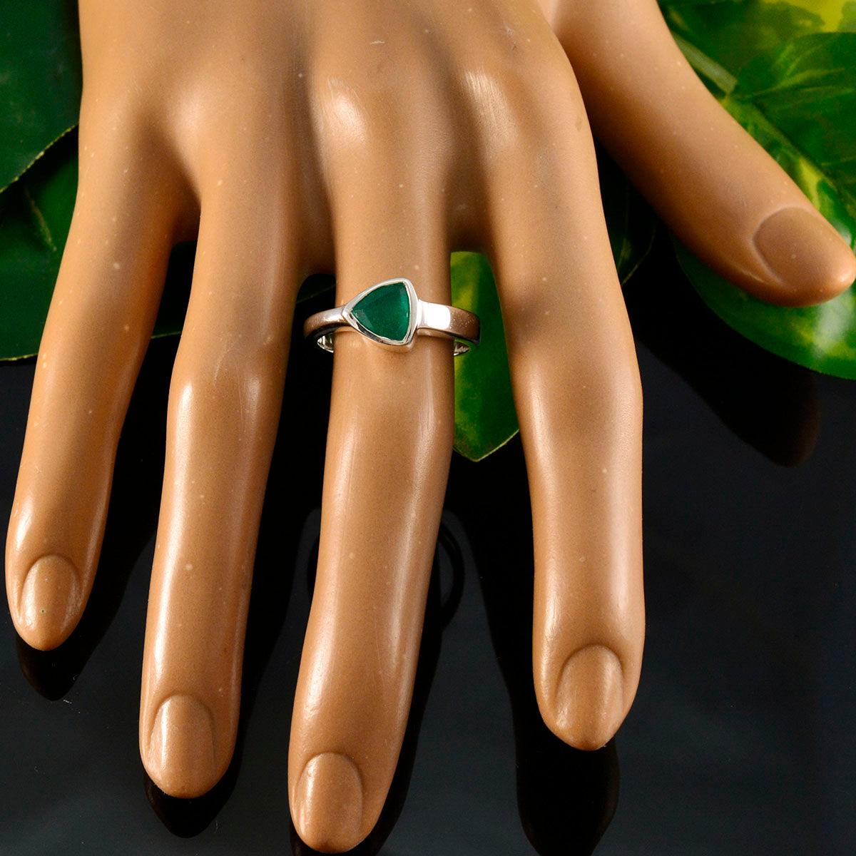 Violet green solitaire ring with triangular stone on silver band displayed on hand model