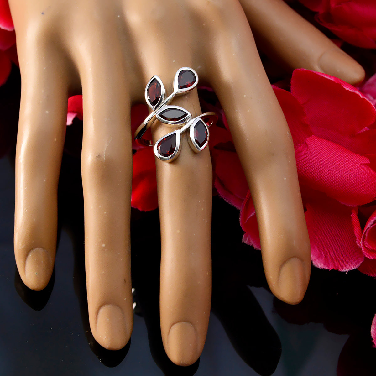 Saanvi abstract red gemstone ring with silver leaf design displayed on hand model with red petals