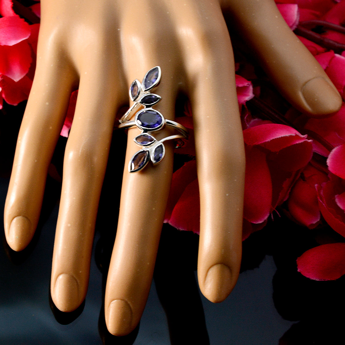 Marie blue gemstone leaf ring on a hand with silver band and purple-blue stones on petals