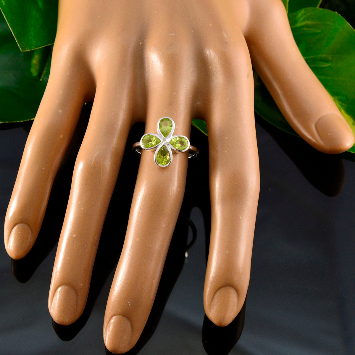 Liyana green gemstone floral ring on mannequin hand with silver band and four petal peridot stones