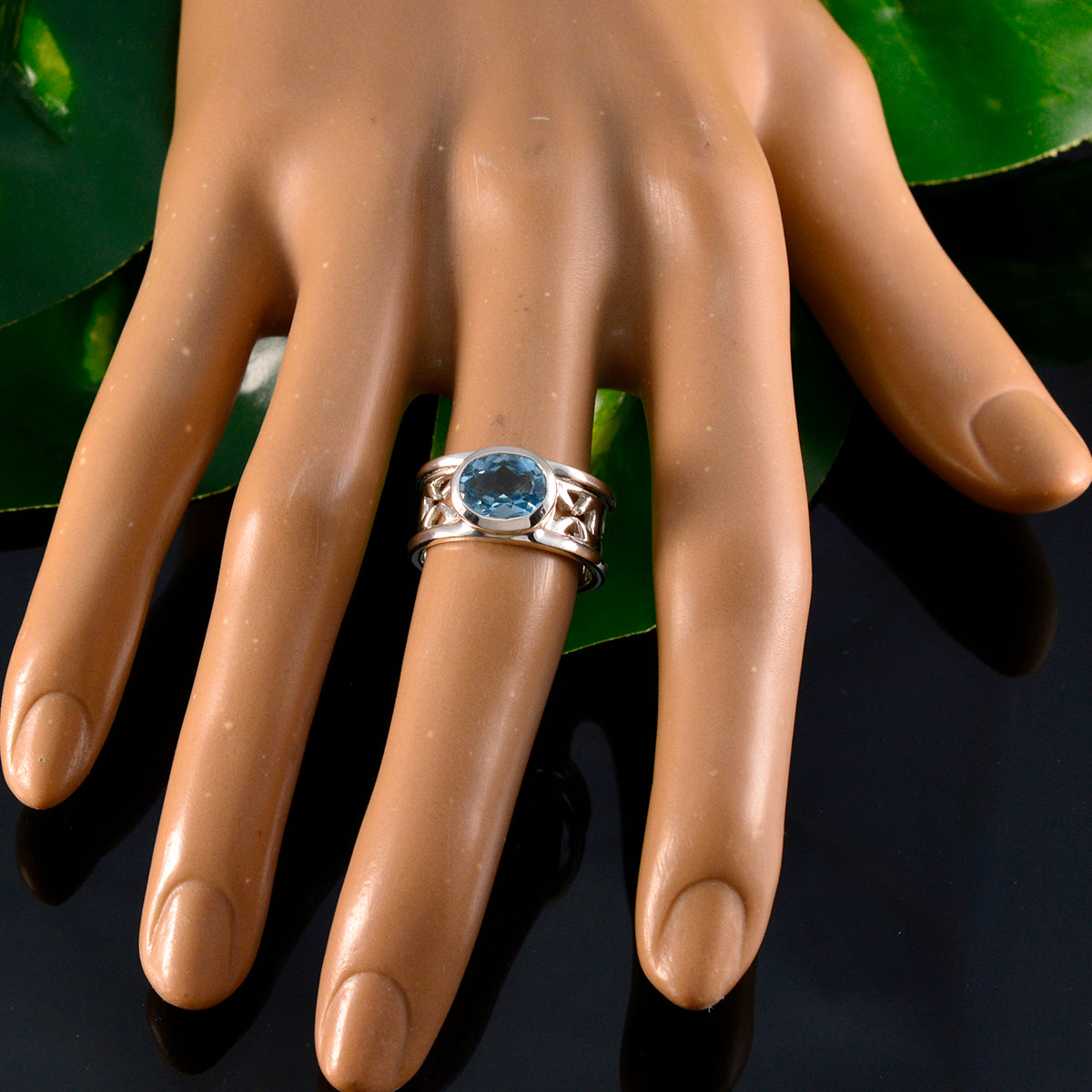 Isabella Irish blue solitaire ring with a round blue gemstone set in a silver ornate band on a display hand