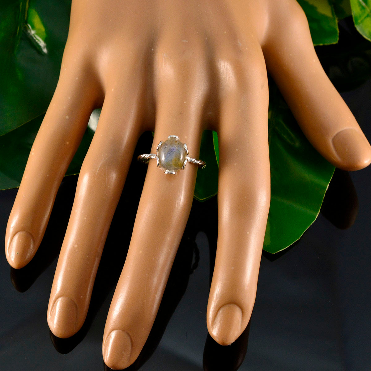 Lakshmi solitaire grey ring with oval stone set on twisted band displayed on mannequin hand