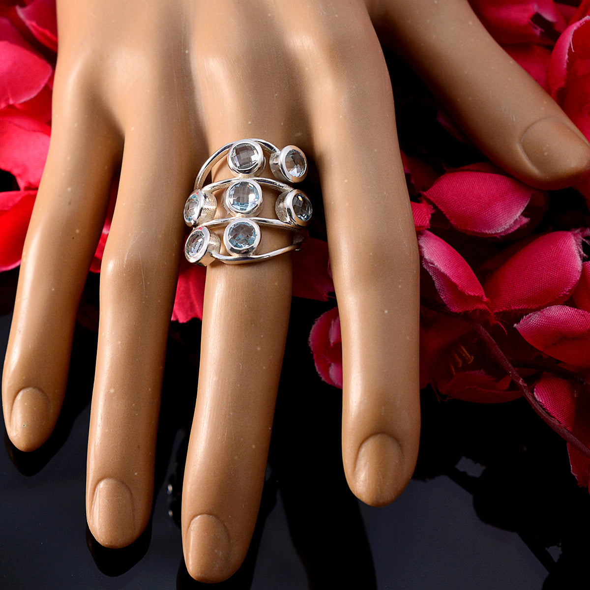 Camila luxurious blue gemstone ring with multiple round stones on silver bands worn on hand
