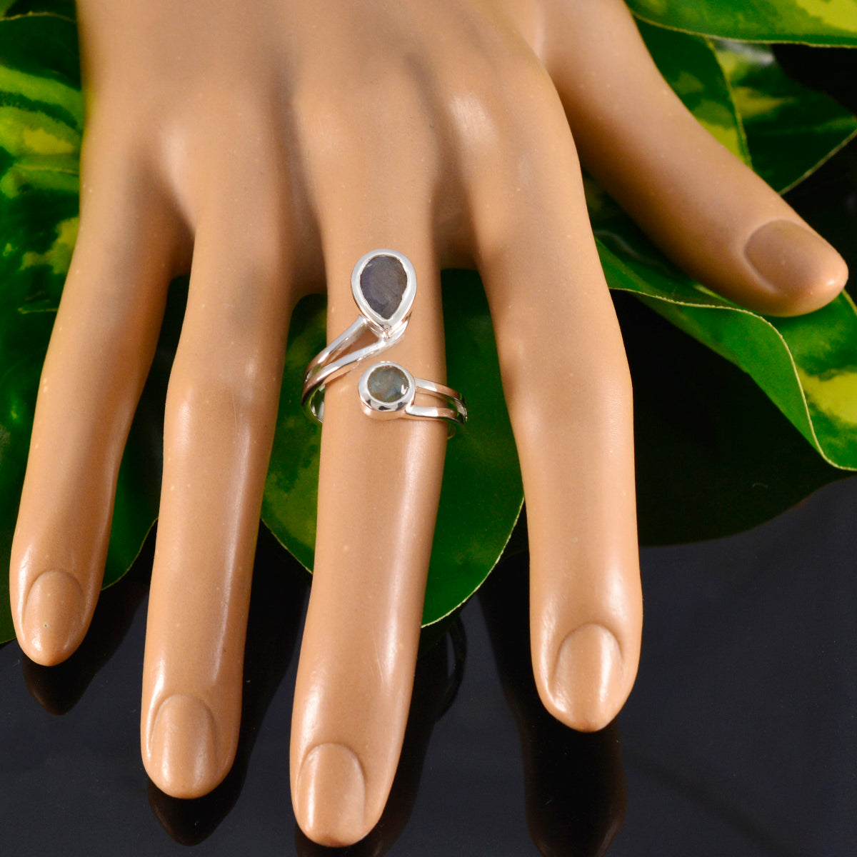 Saanvi luxurious grey toi et moi ring displayed on a mannequin hand with green leaves background