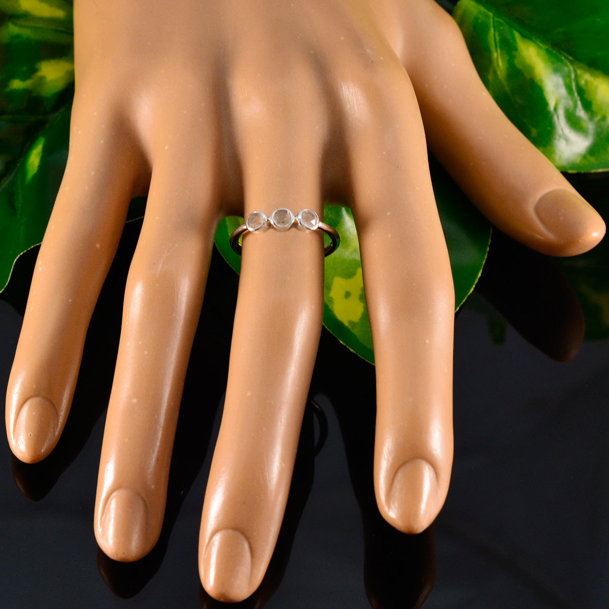 Saanvi modern pink trilogy ring with three pink stones on a silver band displayed on a hand model