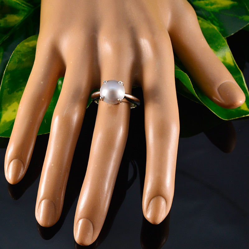 Isla modern solitaire ring with a round pearl set on a silver band displayed on a hand model