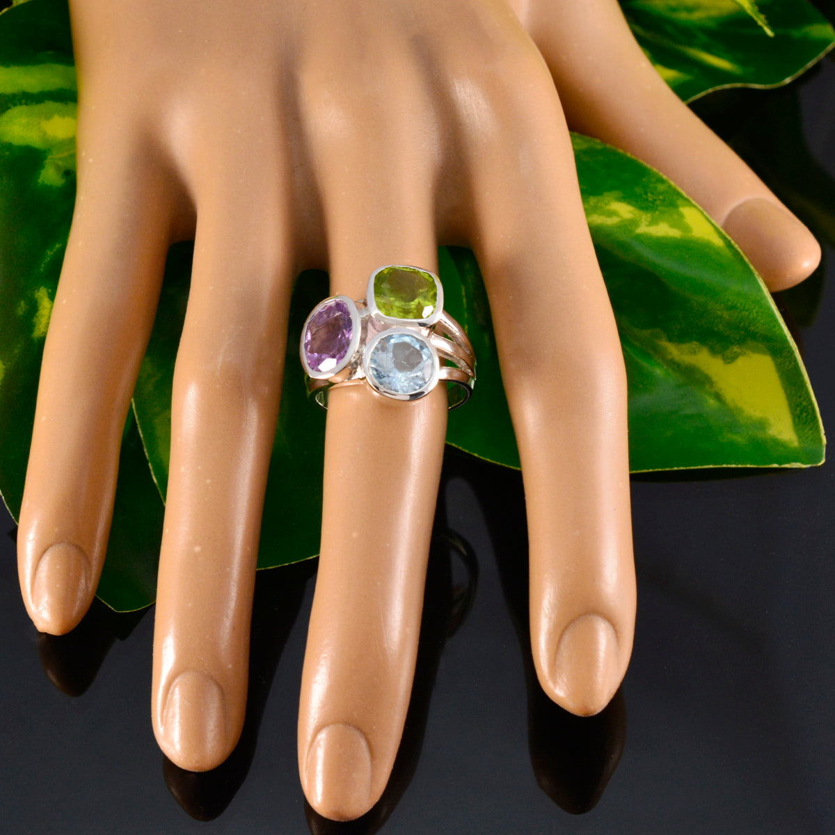 Autumn multicolor gemstone trilogy ring with amethyst peridot and aquamarine set on silver band displayed on a mannequin hand