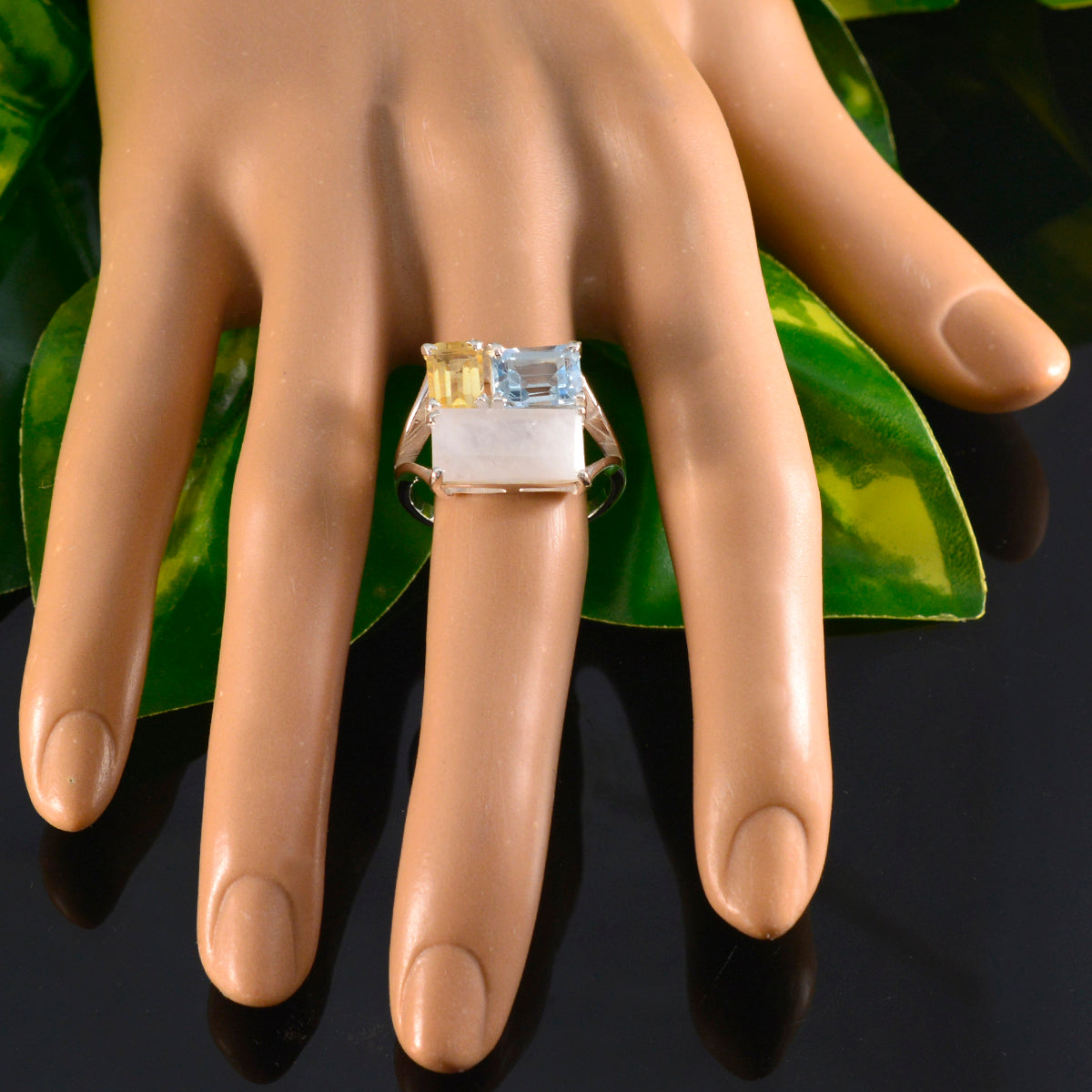 Maya multicolor gemstone trilogy ring with yellow, blue, and white stones on a hand display