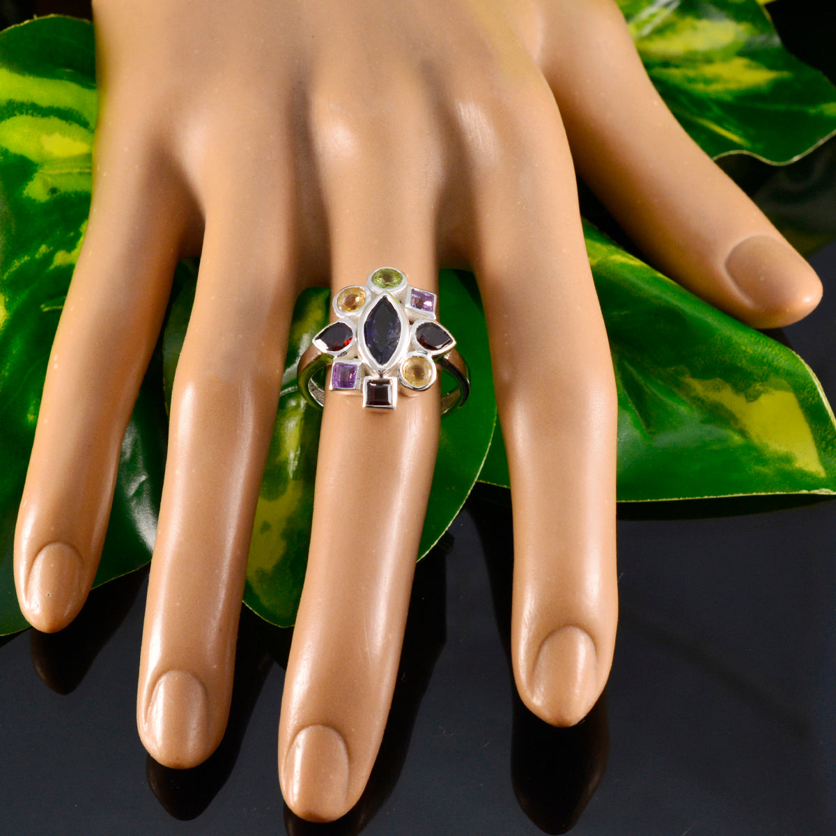Luna multicolor navratna ring with various gemstones on display hand against green leaves background