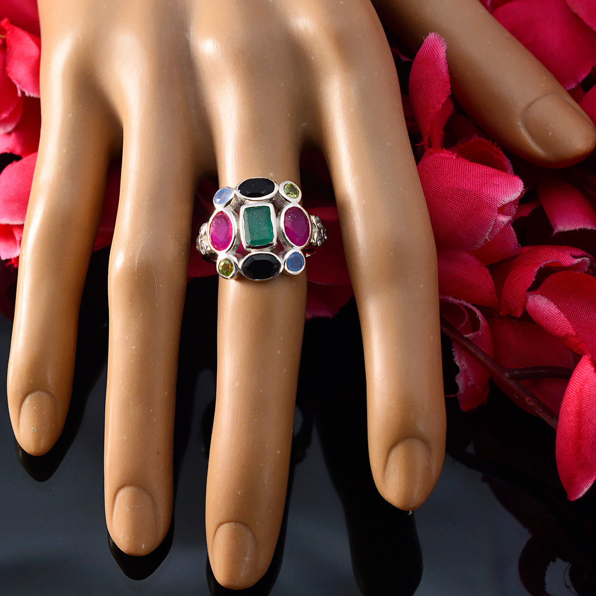 Lorena multicolor Navratna ring with vibrant gemstones displayed on a hand with red flower background