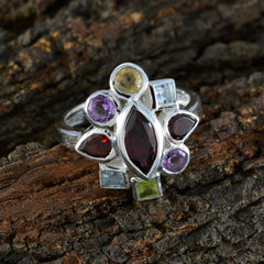 Nia multicolor navratna ring with various gemstones set in silver band on textured wood