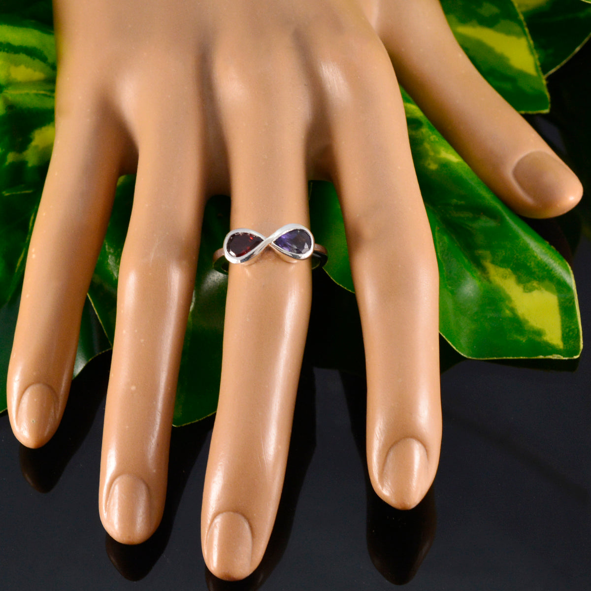 Multicolor toi et moi ring displayed on a mannequin hand surrounded by green leaves