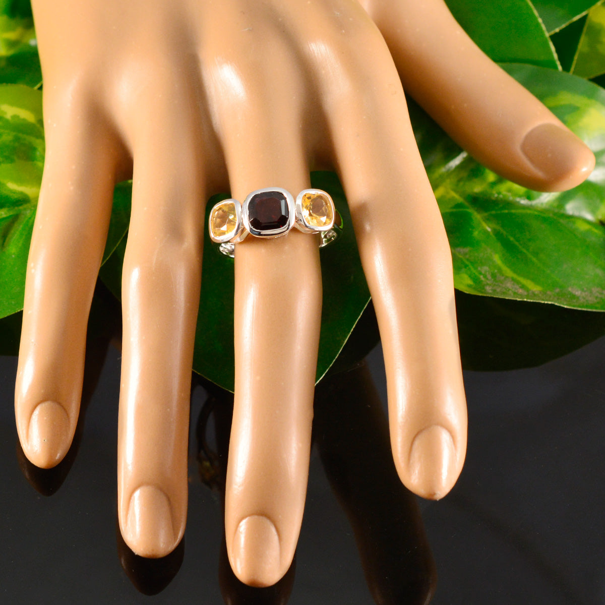 Milagros multicolor trilogy ring with three vibrant gemstones on mannequin hand over green leaves