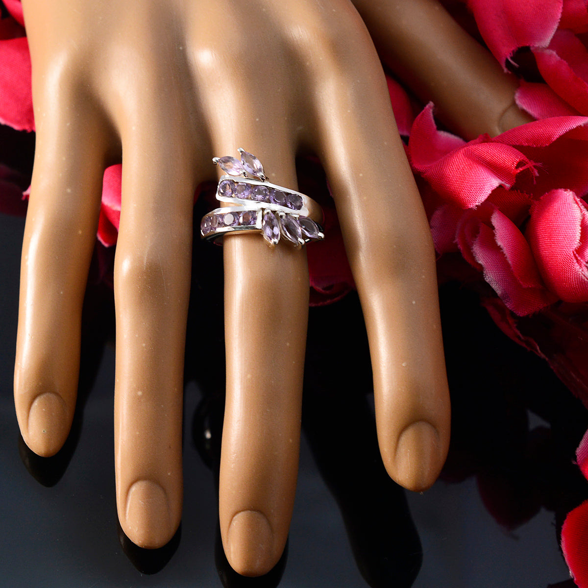Tereza purple gemstone statement ring on mannequin hand with marquise and round stones and pink flower backdrop