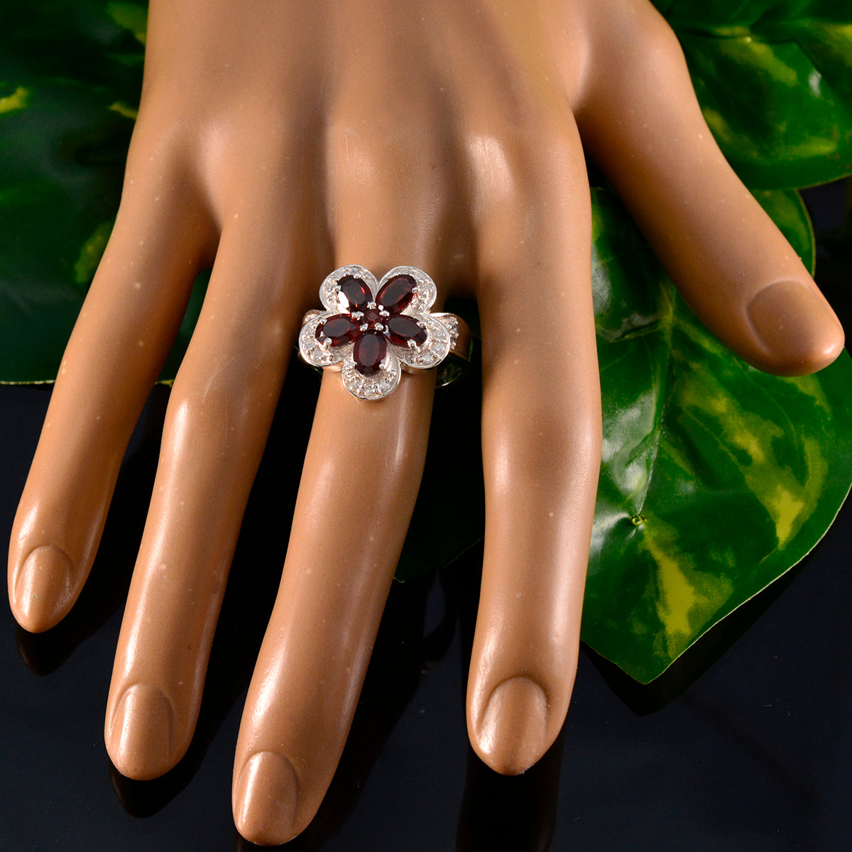 Isla red floral gemstone ring with flower design and clear accent stones on hand display